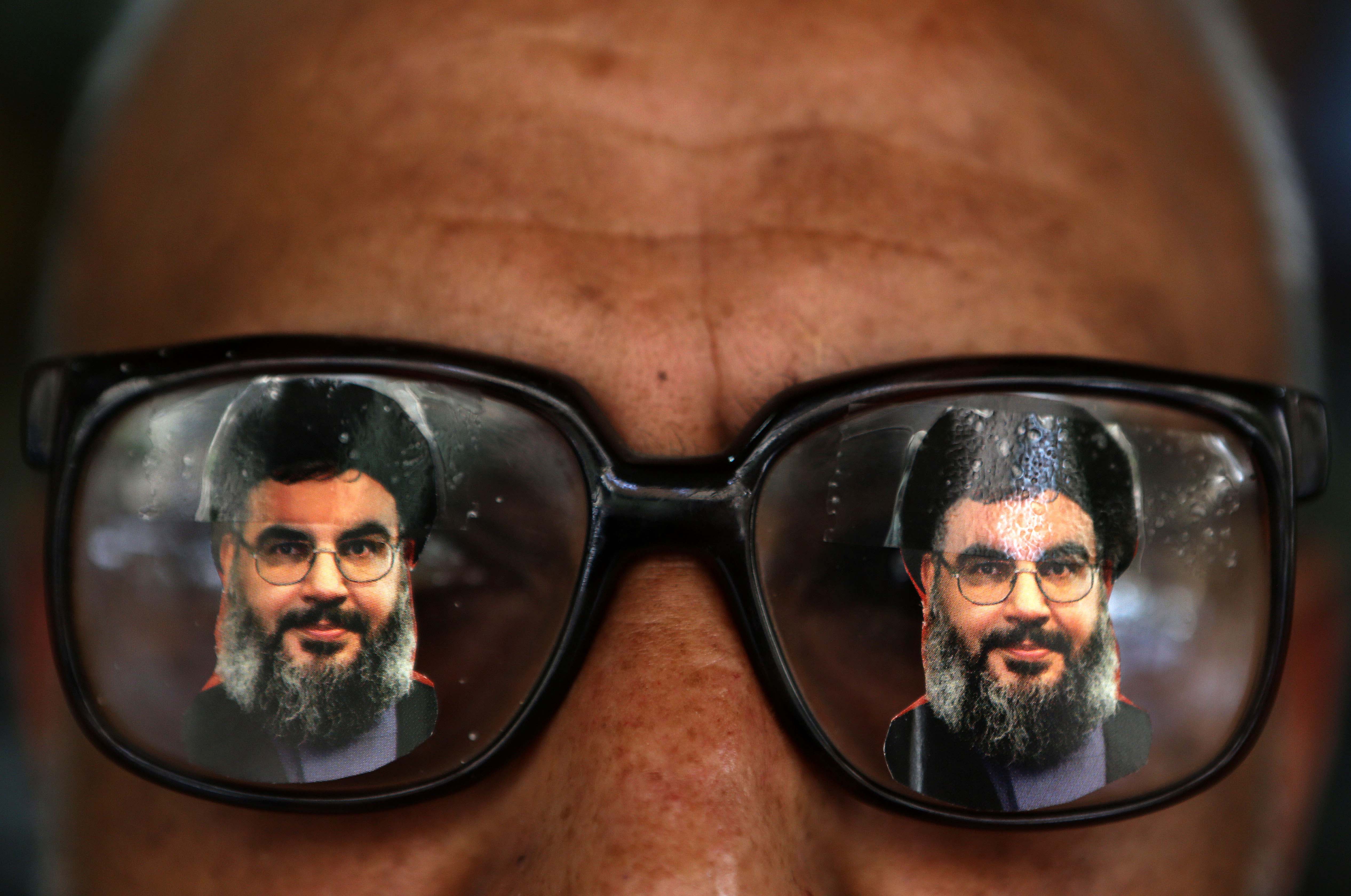 A souvenir shop owner displays glasses decorated with pictures of Hassan Nasrallah
