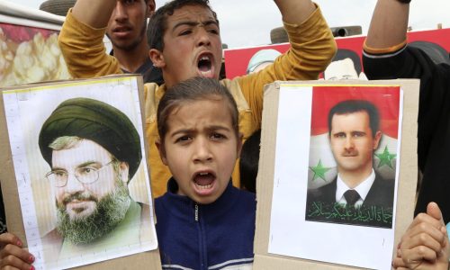 A Syrian refugee girl shout slogans as she holds pictures of Syria's President Bashar al-Assad (R) and Lebanon's Hezbollah leader Sayyed Hassan Nasrallah during a celebration of Syrian forces taking control of the Syrian border town of Yabroud, at Marj al-Khokh refugee camp near Marjayoun village, southern Lebanon March 18, 2014. Syrian forces backed by Hezbollah militants took full control of the town of Yabroud on Sunday after driving out rebels, helping Assad secure the land route connecting the capital Damascus with Aleppo and the Mediterranean coast. The fall of Yabroud, the last rebel bastion near the Lebanese border, could sever a vital insurgent supply line from Lebanon and consolidate government control over a swathe of territory from Damascus to the central city of Homs. REUTERS/Karamallah Daher  (LEBANON - Tags: POLITICS CIVIL UNREST CONFLICT)