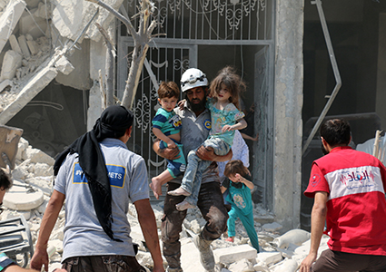A Syrian rescue worker carries children in eastern Aleppo after regime aircraft reportedly dropped explosive-packed barrel bombs on the area, August 27, 2016. Photo: Ameer Alhalbi / AFP