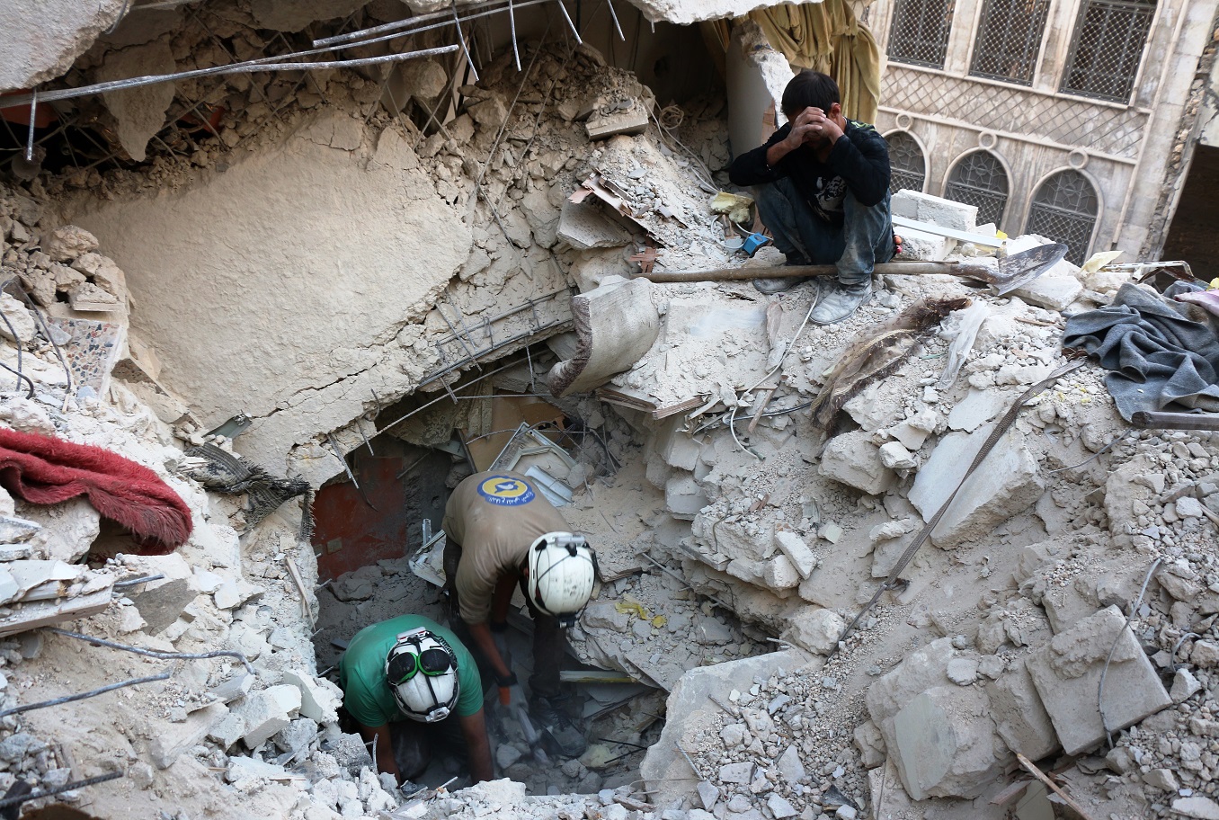 Syrian civil defense volunteers in Aleppo search for victims amid buildings destroyed in an airstrike by government forces, October 4, 2016. Photo: Thaer Mohammed / AFP