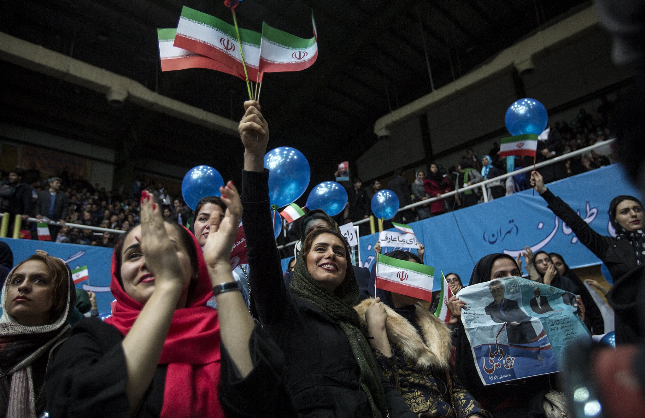Iranian women hold national flags during a reformists campaign meeting in Tehran for the 2016 parliamentary elections, February 20, 2016. Photo: Behrouz Mehri / AFP
