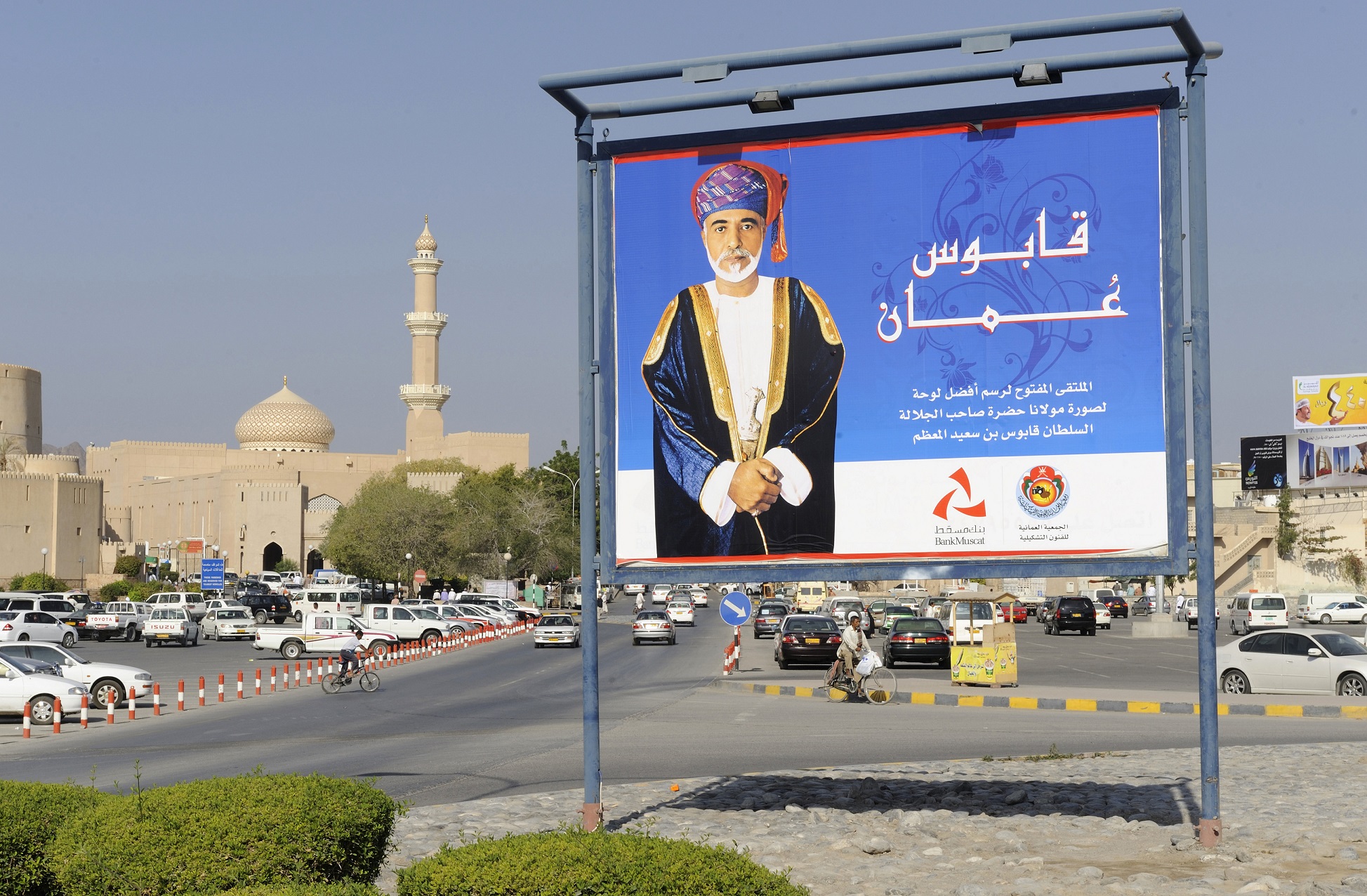 Sultanate of Oman, Ad-Dakhiliyah, Nizwa, bank poster with portrait of Sultan Qaboos, mosque in background (photo: Getty)