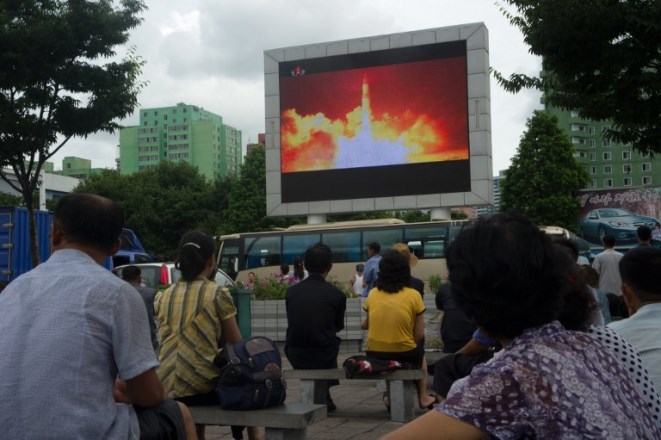 People watch as coverage of an ICBM missile test is displayed on a screen in a public square in Pyongyang on July 29, 2017.
