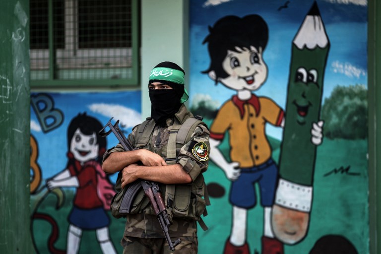 A masked youth cadet of the Ezzedine al-Qassam Brigades, the armed wing of the Palestinian Islamist Hamas movement, stands holding a Kalashnikov assault rifle at a march in the southern Gaza Strip city of Khan Yunis on September 15, 2017.
