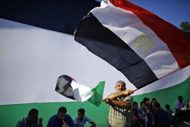 A Palestinian man waves the flags of Egypt and Palestine as people gather in Gaza City to celebrate after rival Palestinian factions Hamas and Fatah reached an agreement on ending a decade-long split following talks mediated by Egypt on October 12, 2017.