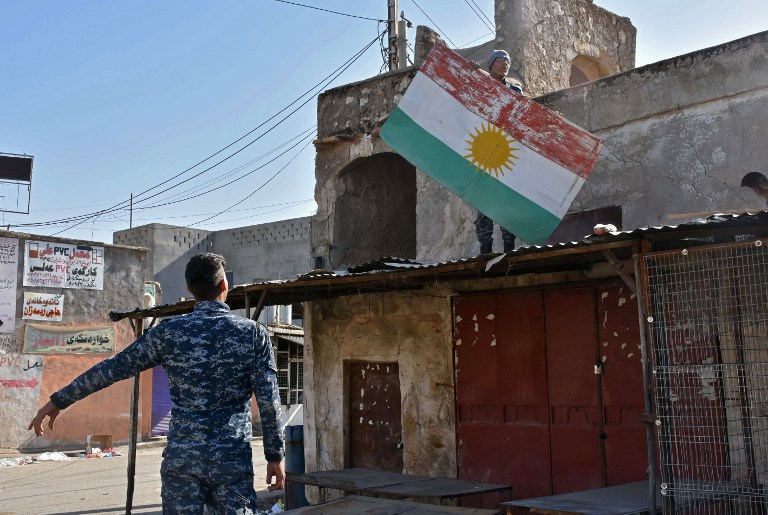 An Iraqi fighter loyal to the federal government carriesd away a sheet metal sign painted with the colours of the Kurdish flag from a building in the region of Altun Kupri, about 50 kilometres (30 miles) from Arbil, capital of autonomous Iraqi Kurdistan, on October 20, 2017.