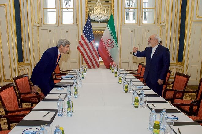 U.S. Secretary of State John Kerry takes his seat across from Iranian Foreign Minister Javad Zarif on January 16, 2016, before a meeting about the implementation of the Joint Comprehensive Plan of Action.