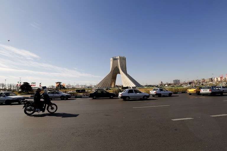 Iranian motorists drive past the Azadi Tower in the capital Tehran on January 13, 2018.