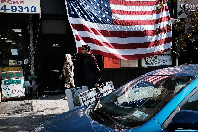 People walk by an American Flag in a Brooklyn community with a large Uzbek community on November 3, 2017 in New York City.