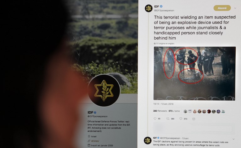 A person reads in Jerusalem on April 19, 2018 a tweet on the Twitter account of the Israeli military suggesting that a photo they distributed shows journalists being willingly used as human shields by Palestinian demonstrators during recent protests in the Gaza Strip.