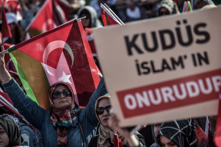 Protesters hold up a placard that reads 'Al Quds is the honor of Islam' as they listen to the speech of the Turkish President during a protest rally in Istanbul on May 18, 2018.