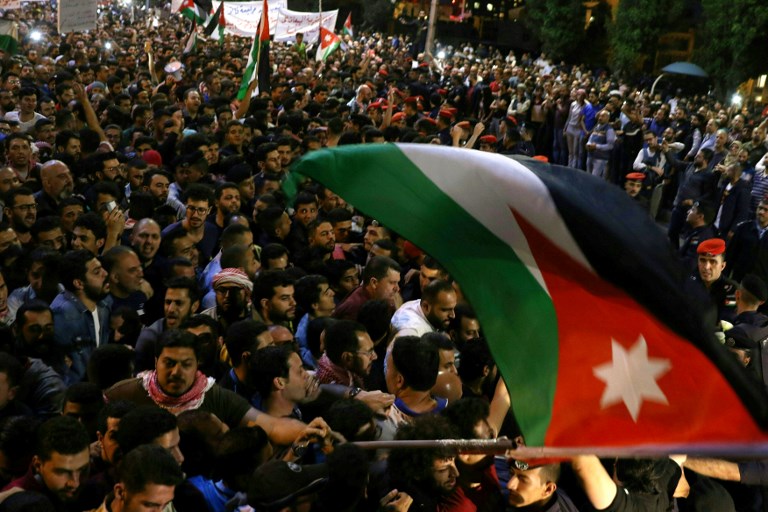 Demonstrators wave a Jordanian flag in front of Jordanian police officers during a protest near the prime minister's office in Amman, Jordan, on June 5, 2018.