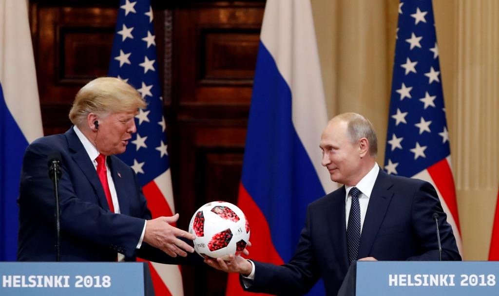 U.S. President Donald Trump receives a football from Russian President Vladimir Putin as they hold a joint news conference after their meeting in Helsinki, Finland July 16, 2018.