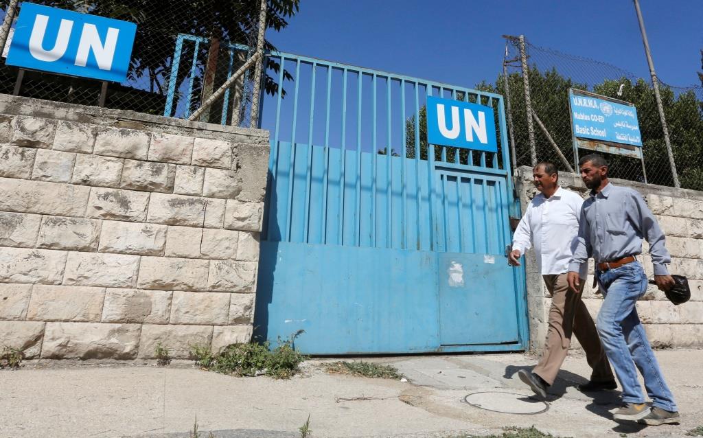 Palestinians pass by the gate of an UNRWA-run school in Nablus in the West Bank August 13, 2018.