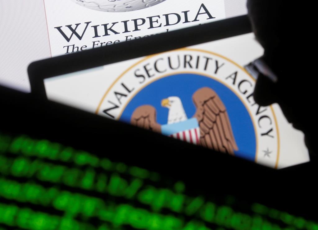 A man is seen near cyber code and the U.S. National Security Agency logo in this photo illustration taken in Sarajevo March 11, 2015. NSA was sued on March 10, 2015, by Wikimedia and other groups challenging one of its mass surveillance programs that they said violates Americans' privacy and makes individuals worldwide less likely to share sensitive information.