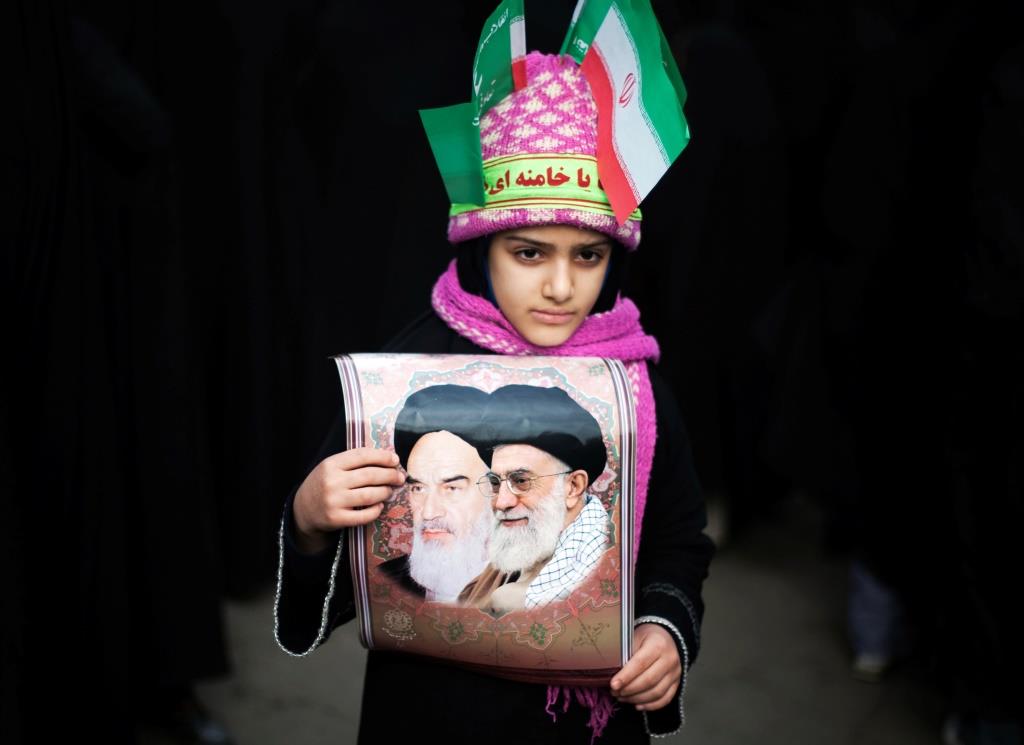 A girl wearing Iranian flags on her hat and a headband that reads