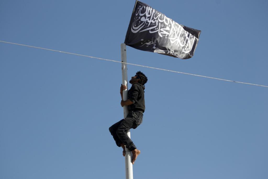A member of al Qaeda's Nusra Front climbs a pole where a Nusra flag was raised at a central square in the northwestern city of Ariha, Idlib province. May 29, 2015.