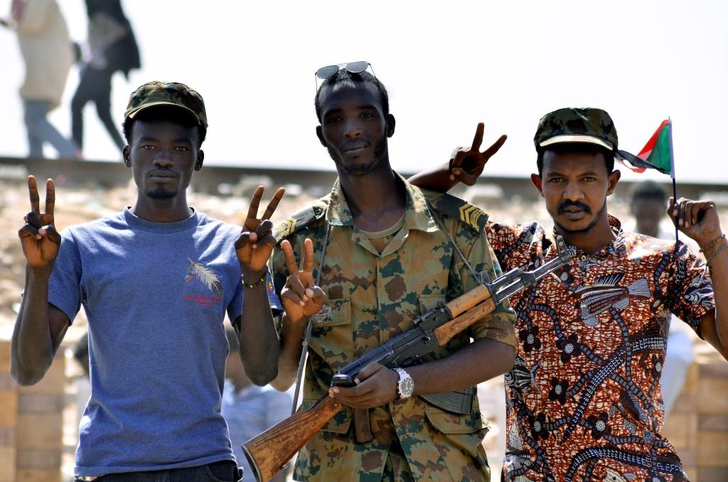 A Sudanese military officer and demonstrators gesture in celebration after Defence Minister Awad Ibn Auf stepped down as head of the country's transitional ruling military council. Khartoum, Sudan, April 13, 2019.
