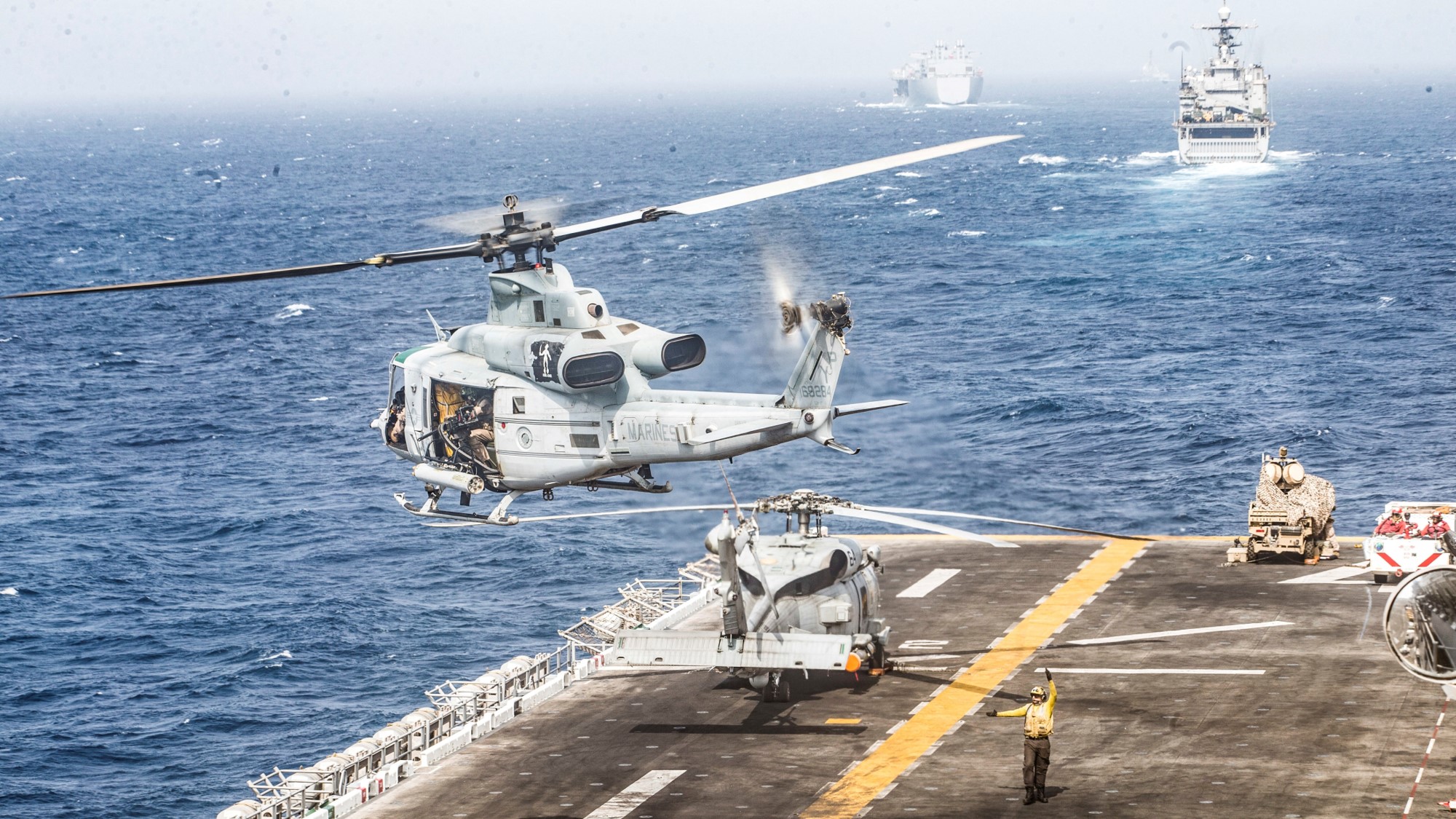 A U.S. Marines UH-1Y Venom helicopter takes off from the flight deck of the U.S. Navy amphibious assault ship USS Boxer, near a Light Marine Air Defense Integrated System (LMADIS) counter-unmanned aircraft system mounted on a vehicle parked at the bow, during its transit through Strait of Hormuz in Gulf of Oman, Arabian Sea, July 18, 2019.