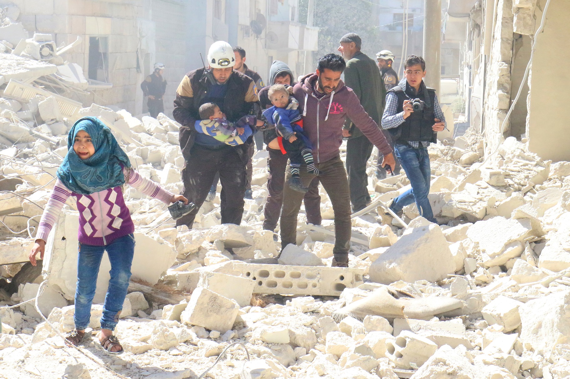 People and a civil defence personnel carry children at a damaged site after an air strike on rebel-held Idlib city, Syria March 19, 2017.