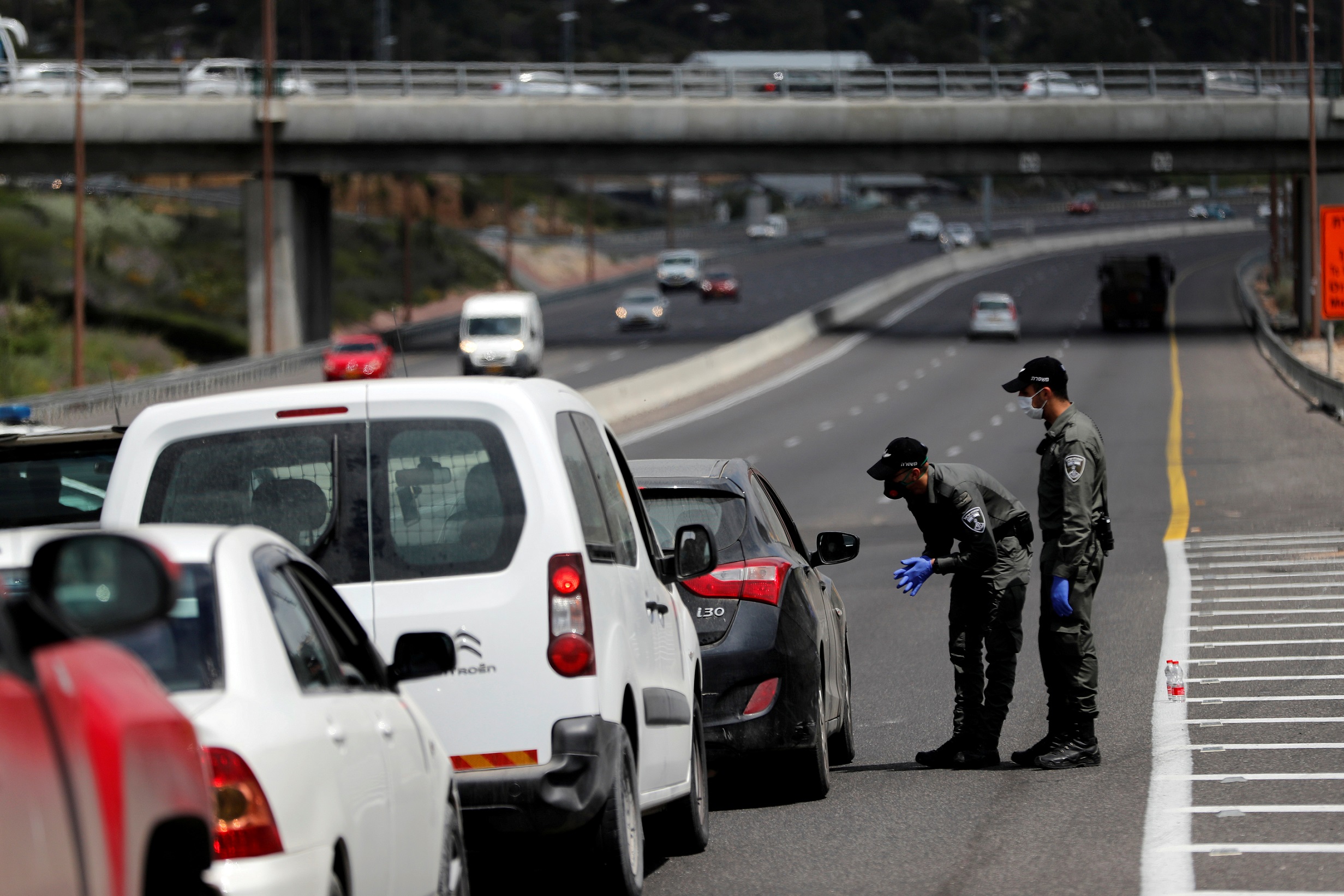 Border policemen chat to a driver at a roadblock set-up by police as they begin to enforce a national lockdown to fight the spread of the coronavirus disease (COVID-19) on a road leading to Jerusalem, near Ein Hemed