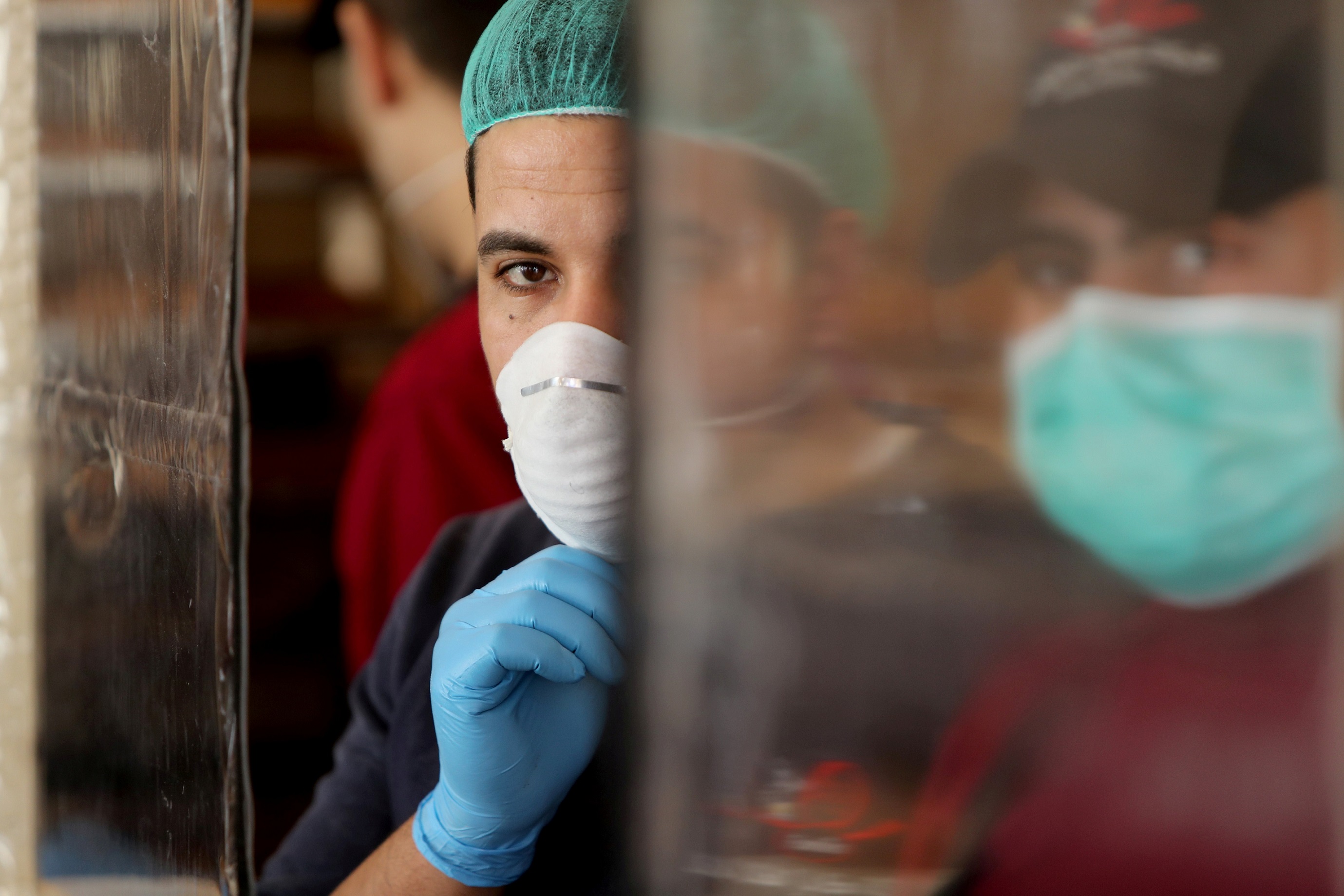 Palestinians, wearing masks as a preventive measure against the coronavirus disease, work in a bakery in Gaza City March 22, 2020.